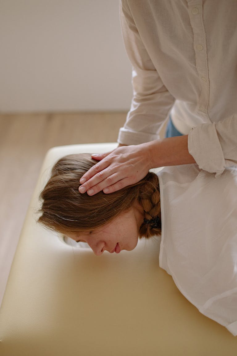 Woman receiving a relaxing head massage therapy on a table indoors.