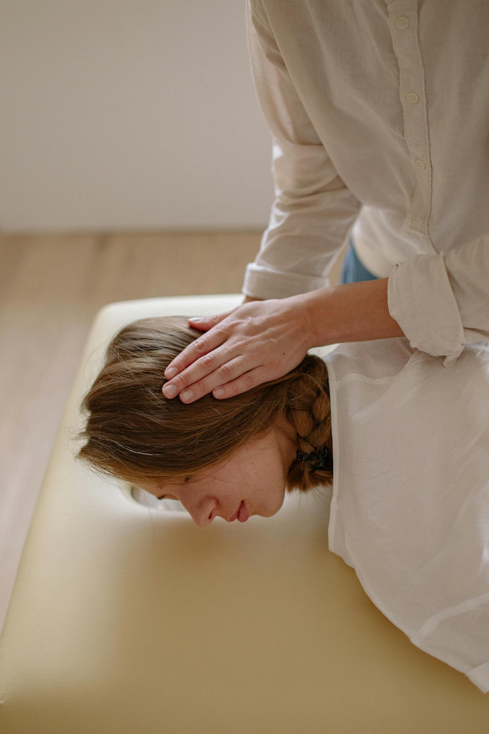 Woman receiving a relaxing head massage therapy on a table indoors.